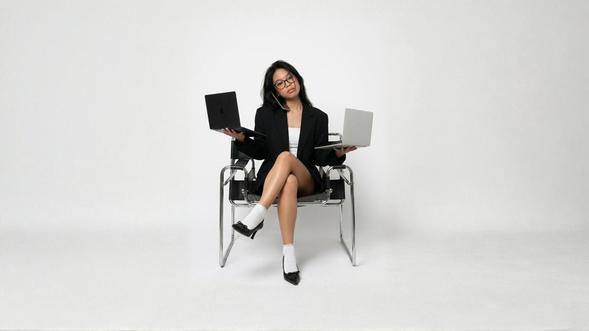 Jhammel seated in a studio holding two laptops